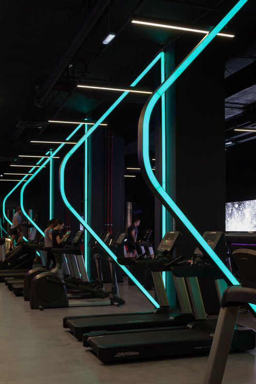 there are many treadmills lined up in the gym with neon lights on them