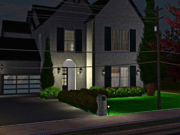 a night scene of a two story house with green grass and bushes in front of it