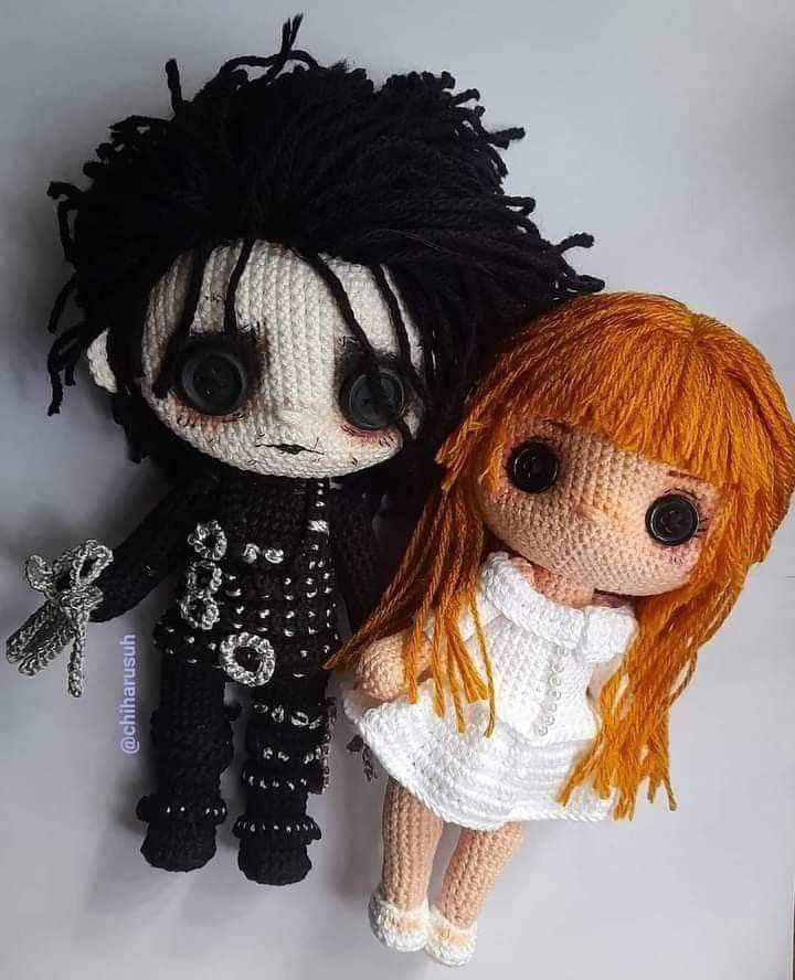 two crocheted dolls sitting next to each other on top of a white surface