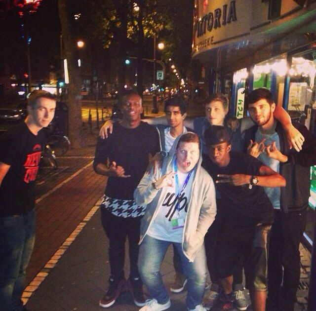 a group of young men standing next to each other in front of a building at night