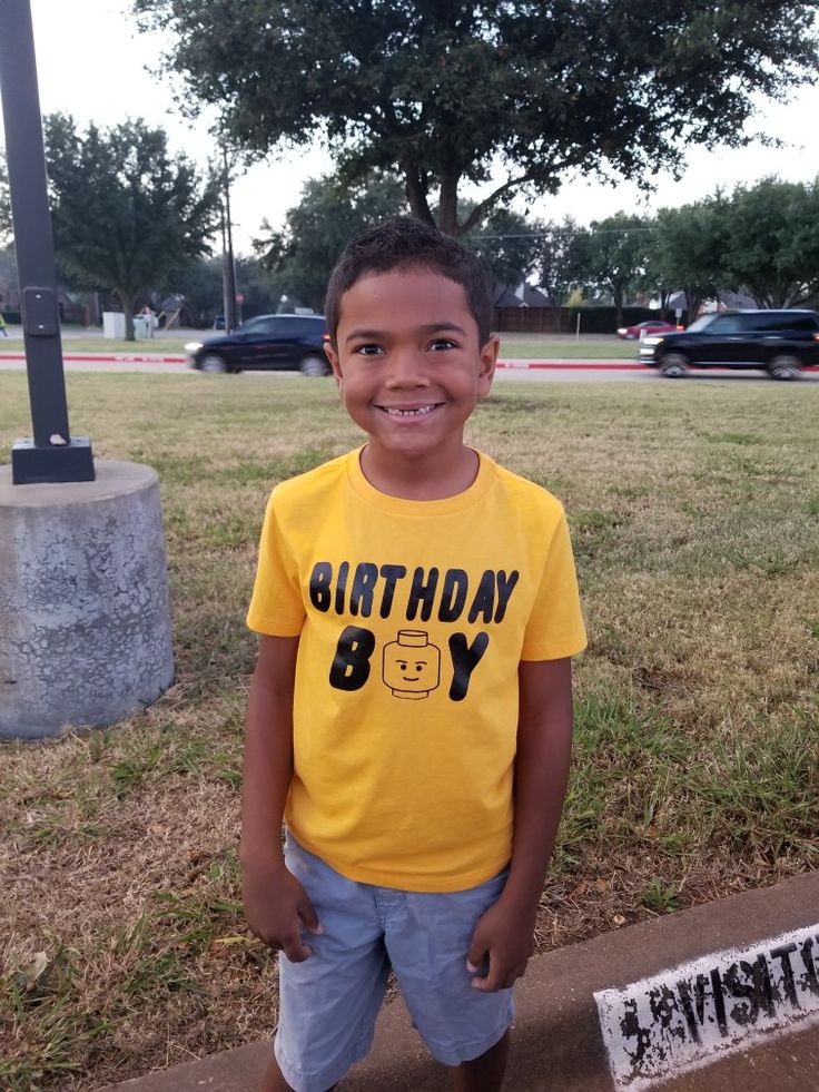 a young boy standing in front of a sign with the words birthday boy on it