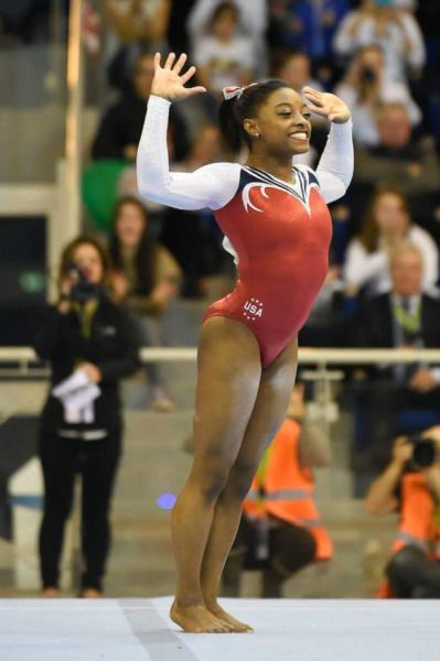 a woman standing on top of a balance beam in front of a crowd at a competition