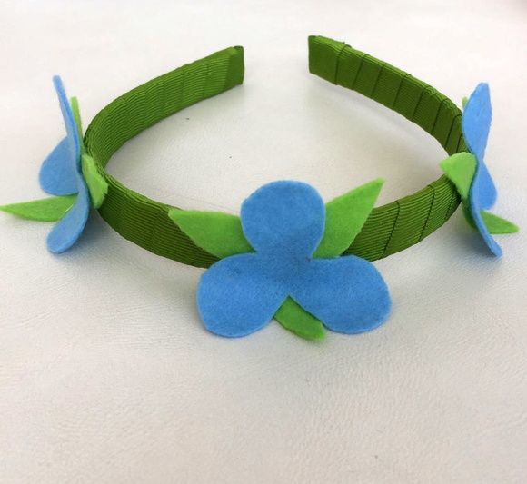 a green and blue flower headband on a white surface with one flower pinned to the side