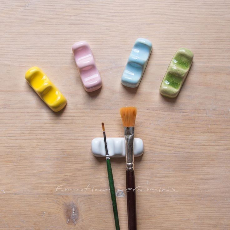 the paint brushes are sitting next to different colored pill shaped objects on top of a wooden table