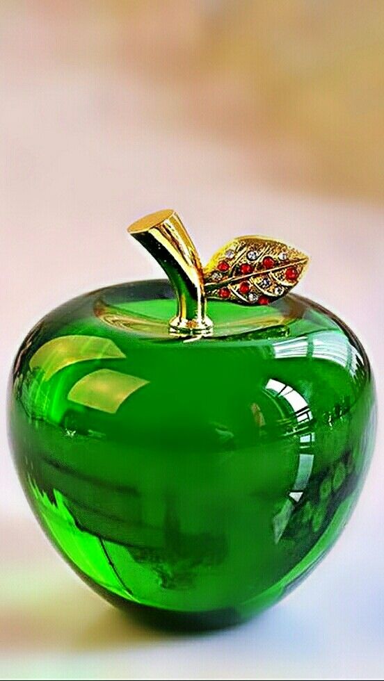 a green glass apple with a gold leaf on top