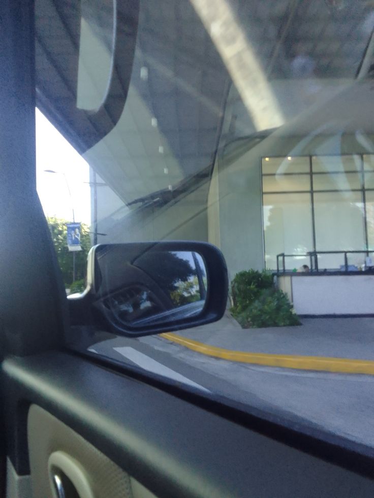 the rear view mirror of a car is shown in front of a building with windows