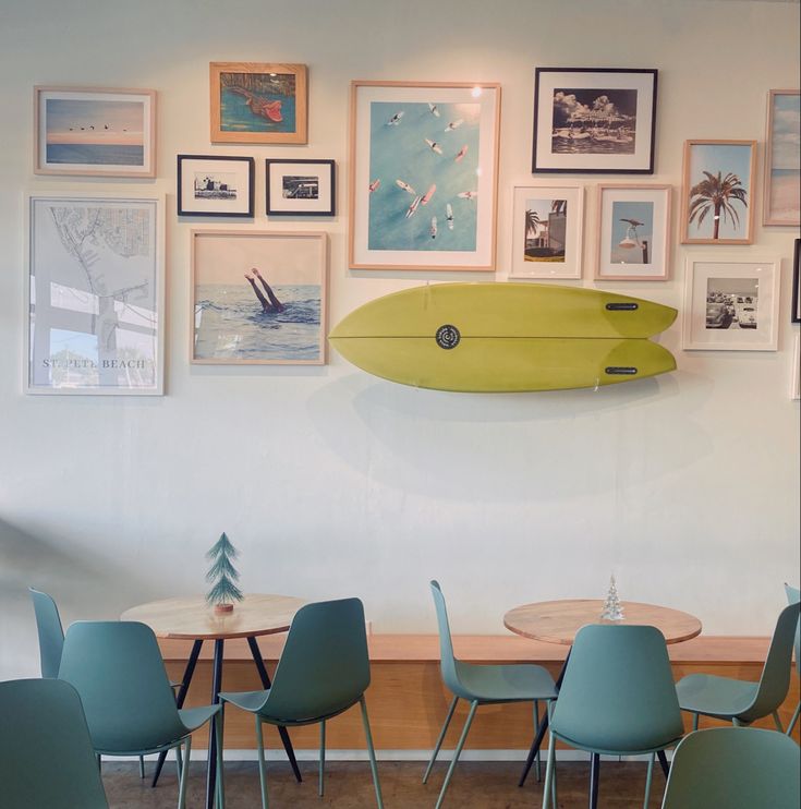 a surfboard mounted to the wall above a table and chairs in a room with pictures on the wall