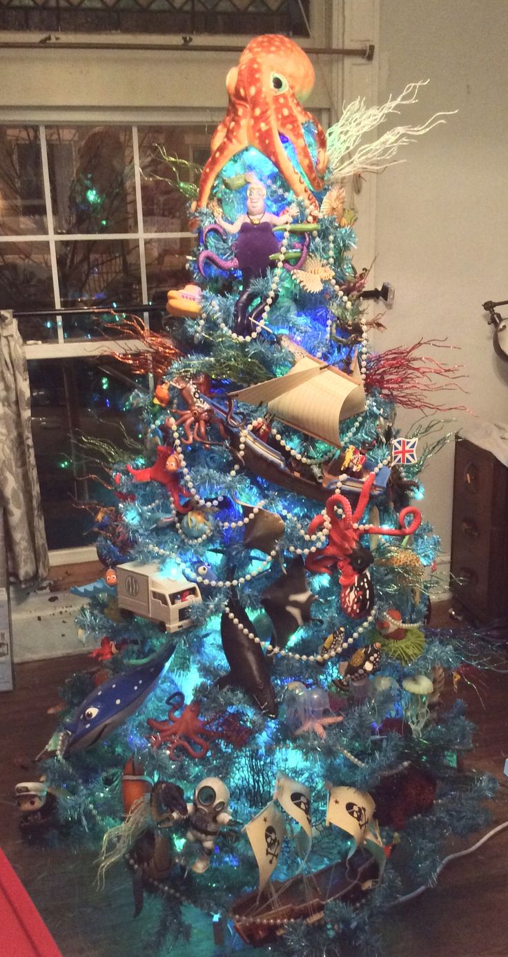 a blue christmas tree decorated with an octopus and other sea creatures, under a window