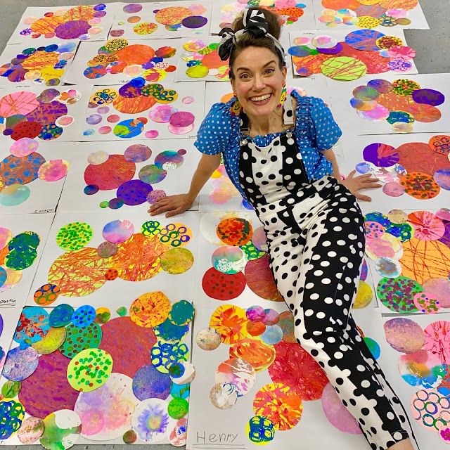 a woman sitting on top of a floor covered in lots of colorful paper flowers and circles