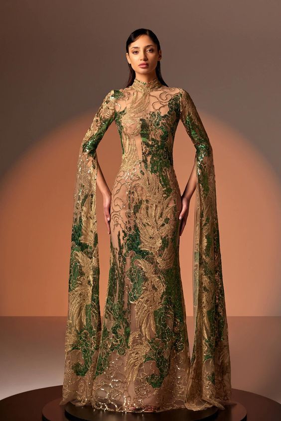 Description Gold Column, Long dress Cape shape, Long Sleeves Closed neckline Embroidered lace Modifications Accepted Custom Measurements Accepted Dry Clean Evening Dress Made in Lebanon 824 Luxury Cape Gown For Banquet, Luxury Cape Gown For Formal Occasions, Luxury Cape Gown For Gala, Luxury Gown With Lace Trim For Ceremonies, Luxury Cape Sleeves Gown For Eid, Luxury Cape Sleeves Gown For Prom, Luxury Cape Gown With Draped Sleeves, Luxury Cape Sleeves Gown For Gala, Luxury Gown With Fitted Bodice And Cape Sleeves