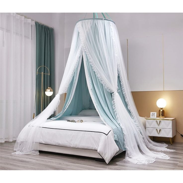 a canopy bed with white sheets and blue drapes on the top, in a bedroom