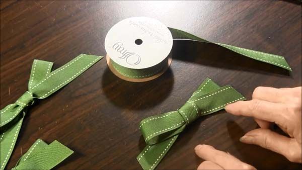 someone is tying a green ribbon on top of a wooden table