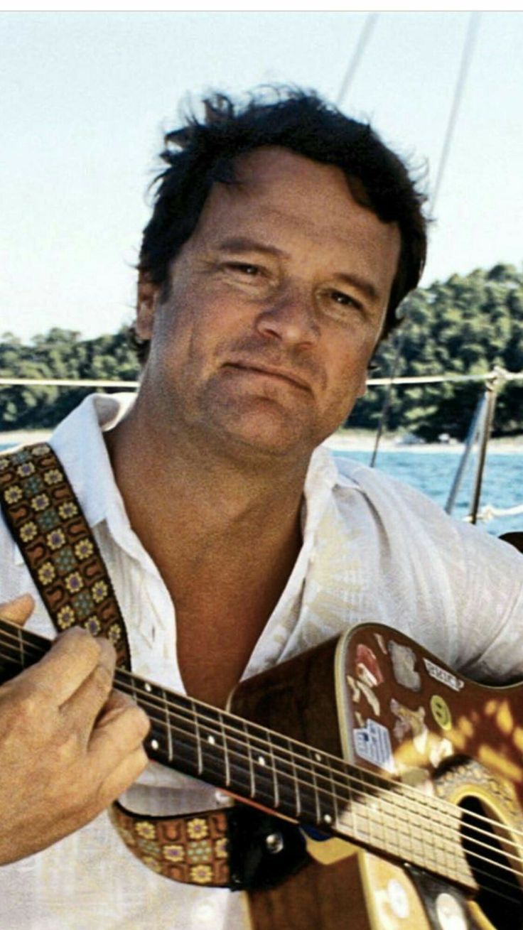 a man is playing an acoustic guitar on a boat