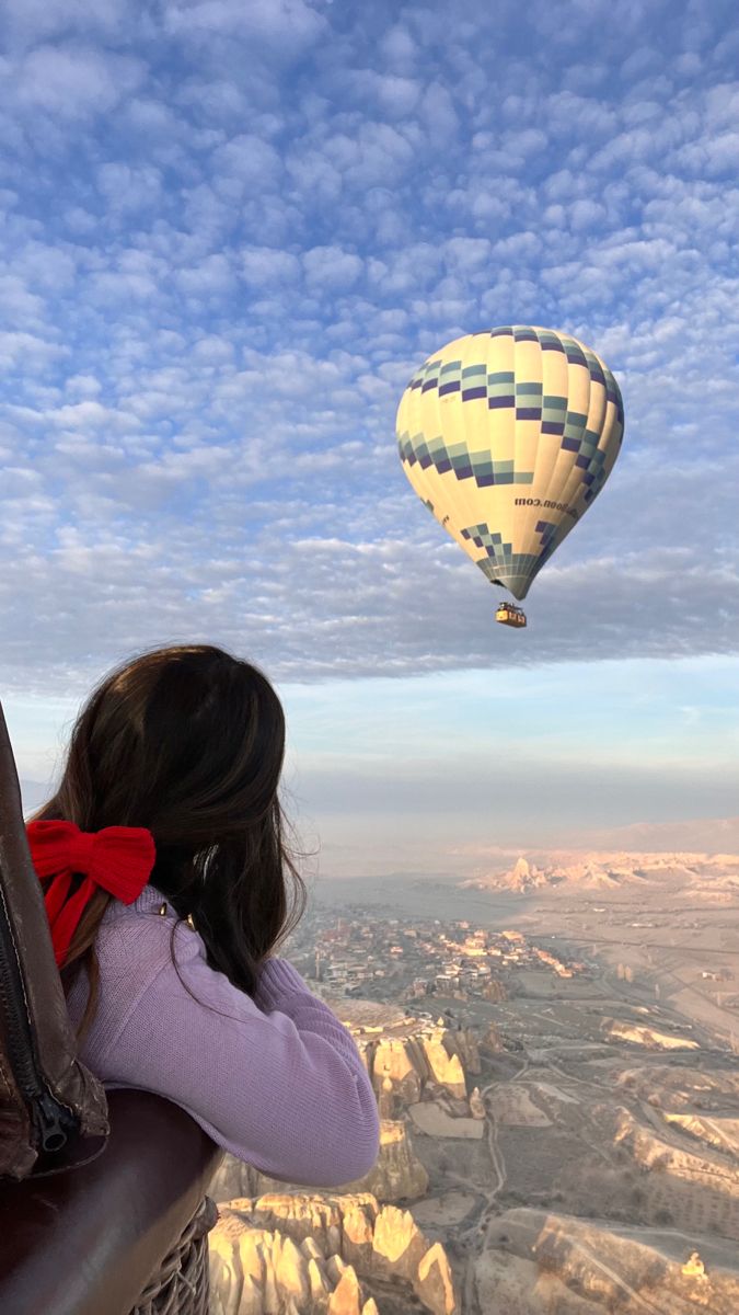 a woman looking out at the sky with a hot air balloon in the background