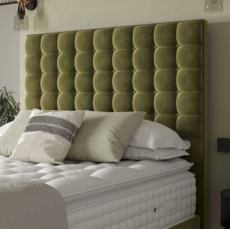 a green headboard with pillows on top of it and a plant in the corner