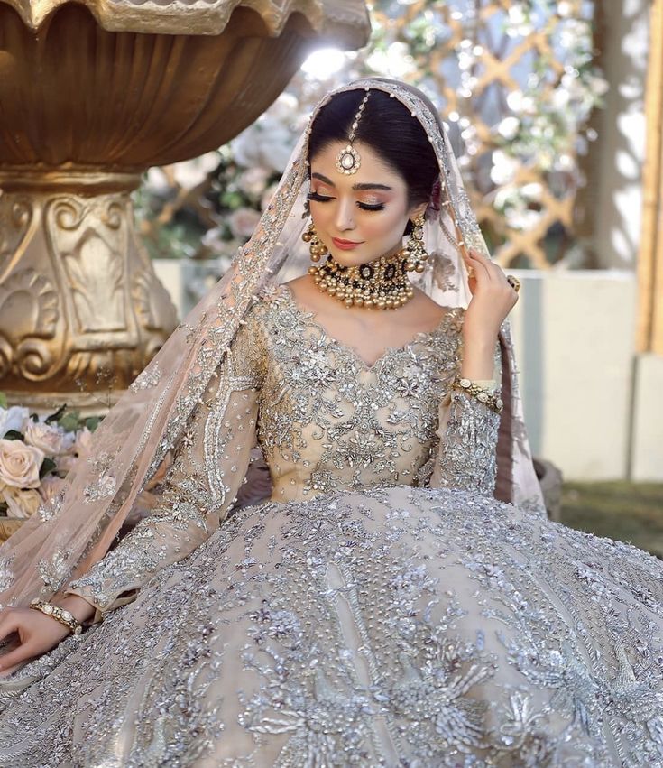 a woman in a bridal gown sitting on the ground next to a flower pot