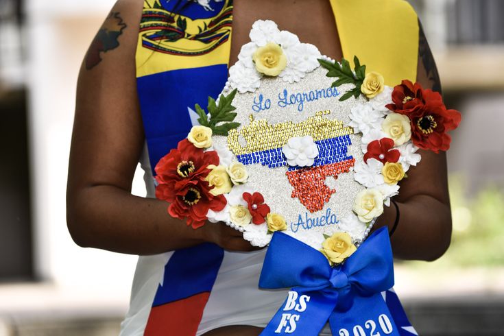 a woman holding a bouquet of flowers in front of her face and wearing a sash