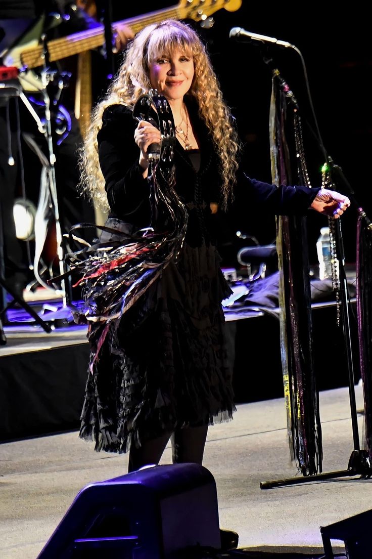 a woman standing in front of a microphone on stage