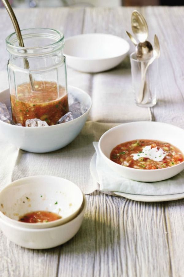 three bowls of soup on a table with spoons and utensils next to them