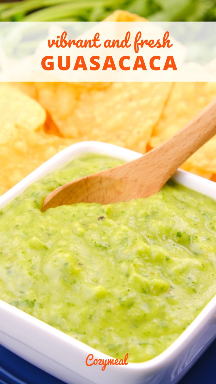 guacamole in a white bowl with a wooden spoon and green beans on the side