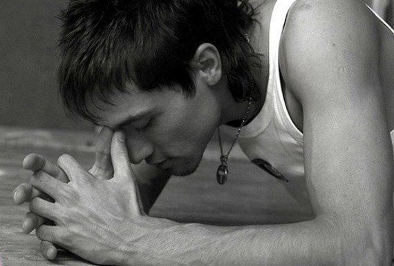 a black and white photo of a man holding his hand to his face while looking down