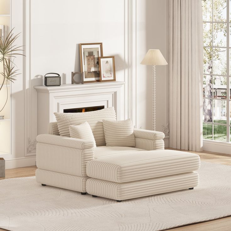 a living room with a white couch and chair in it's centerpiece, next to a fireplace