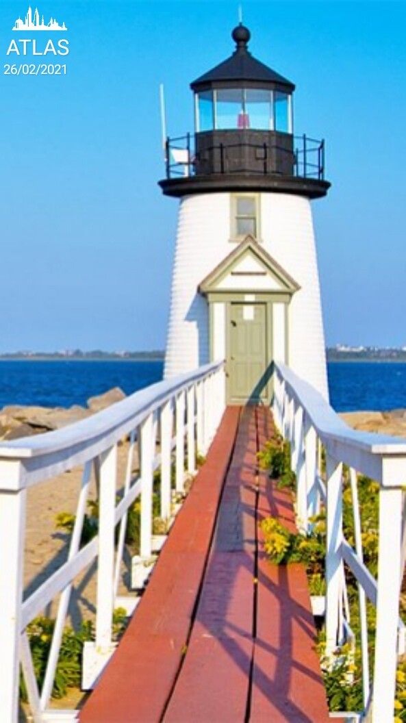 a white lighthouse with a red walkway leading to it