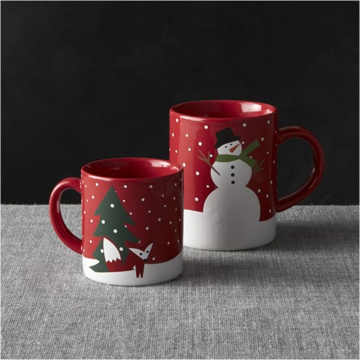 two red and white coffee mugs with snowmen on them, one is holding a christmas tree