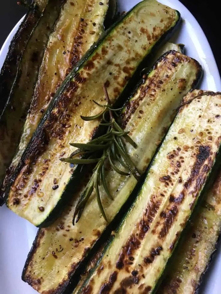 grilled zucchini on a white plate with rosemary