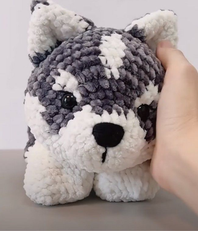 a hand holding up a stuffed animal made out of crocheted yarn with black and white stripes