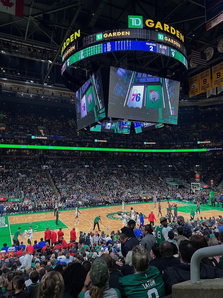 a large group of people watching a basketball game on the big screen tv in an arena