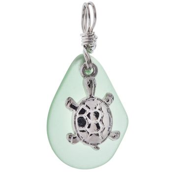 a glass charm with a silver plated turtle on it's face and the words seaglass