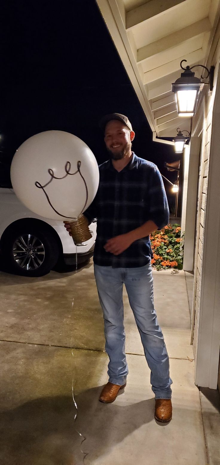 a man holding a balloon with a face drawn on it