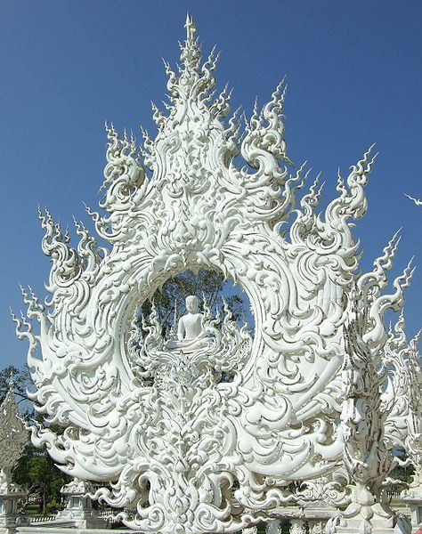 an intricately carved white structure in the middle of a park