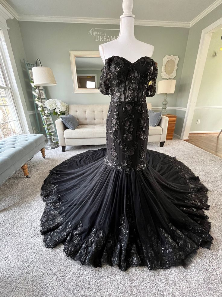 a black dress is on display in a living room with white carpet and couches