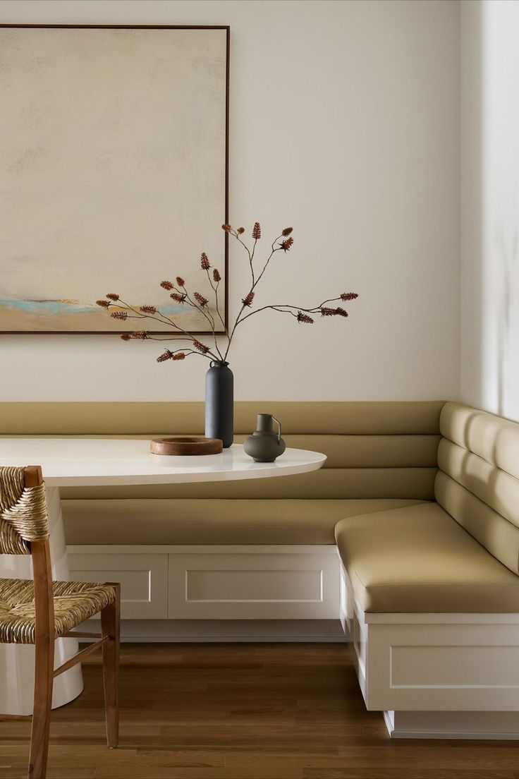 a white table and bench in a room with a painting on the wall behind it