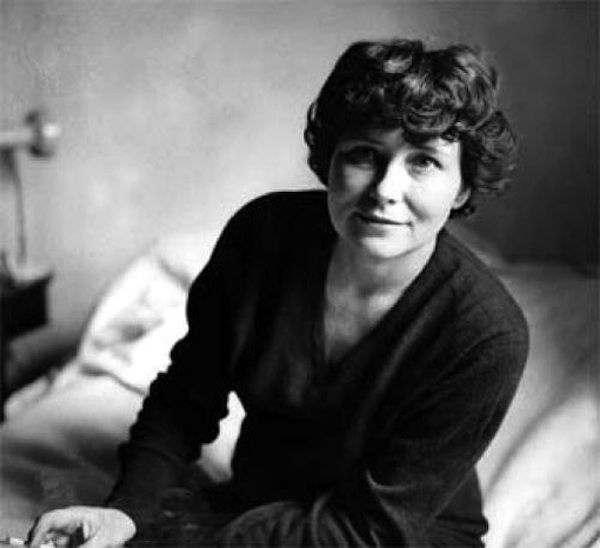 black and white photograph of a woman sitting on a bed