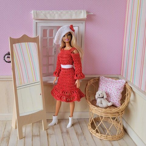 a doll is standing next to a mirror in a room with pink walls and wooden flooring