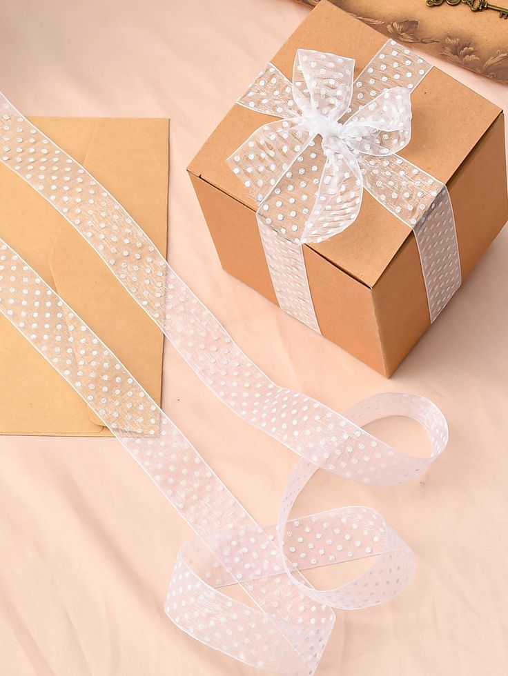 a box with a white ribbon on it next to a brown box with a white bow