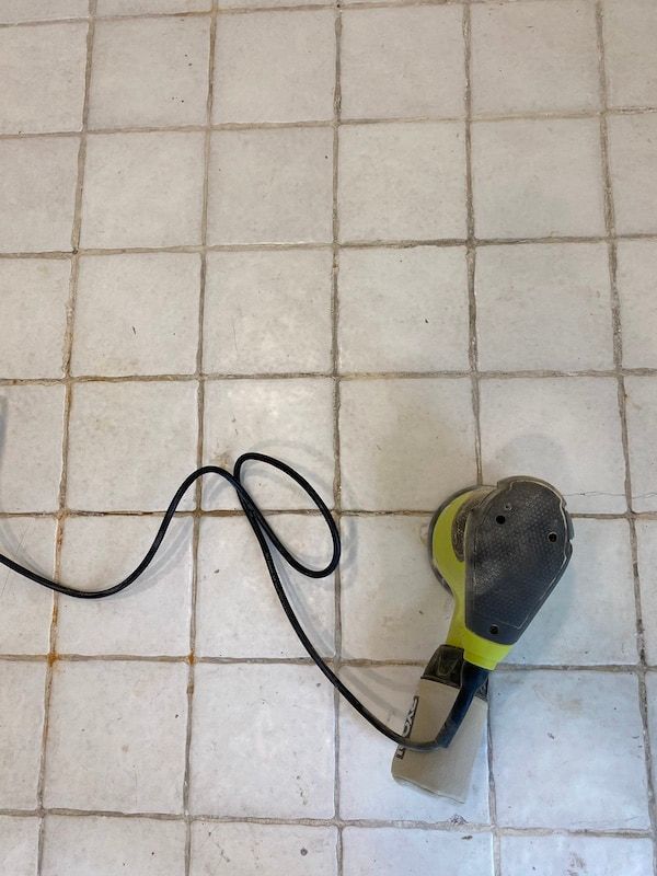 a yellow and black blow dryer sitting on top of a white tiled floor