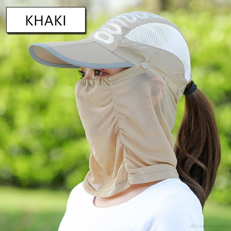 a woman wearing a hat and covering her face with a mask on top of her head