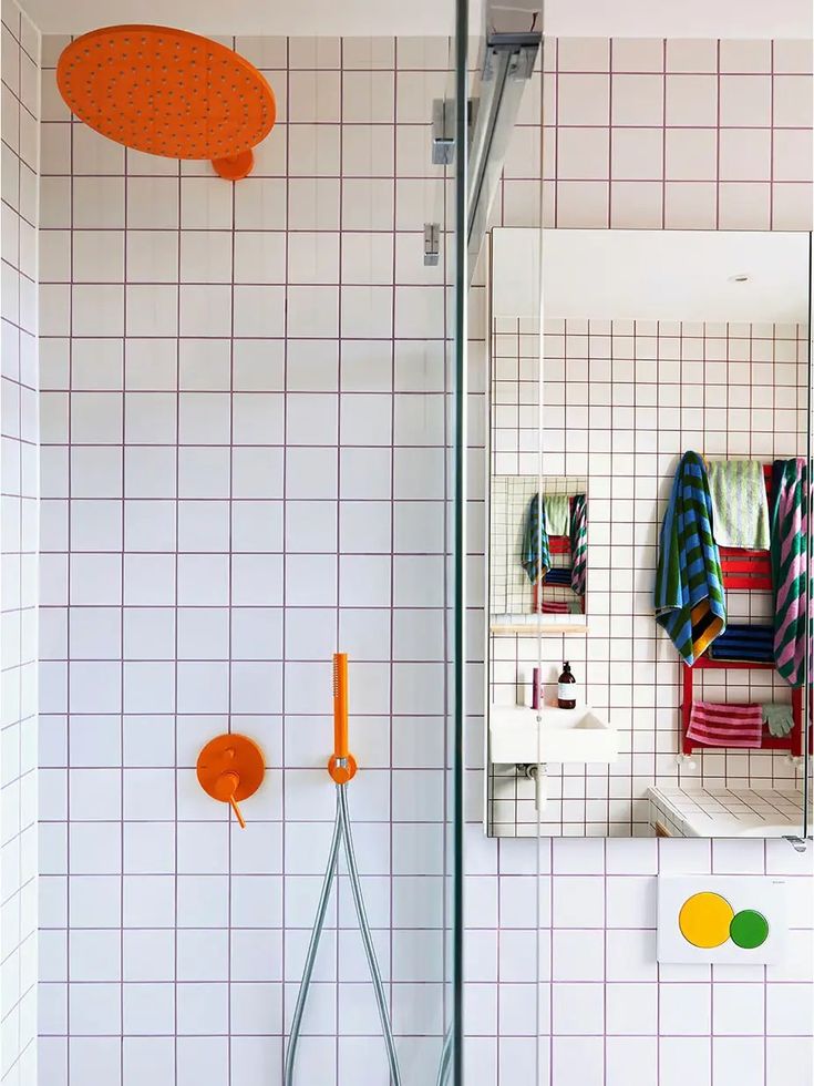 a bathroom with tiled walls and flooring, including an orange shower head in the corner