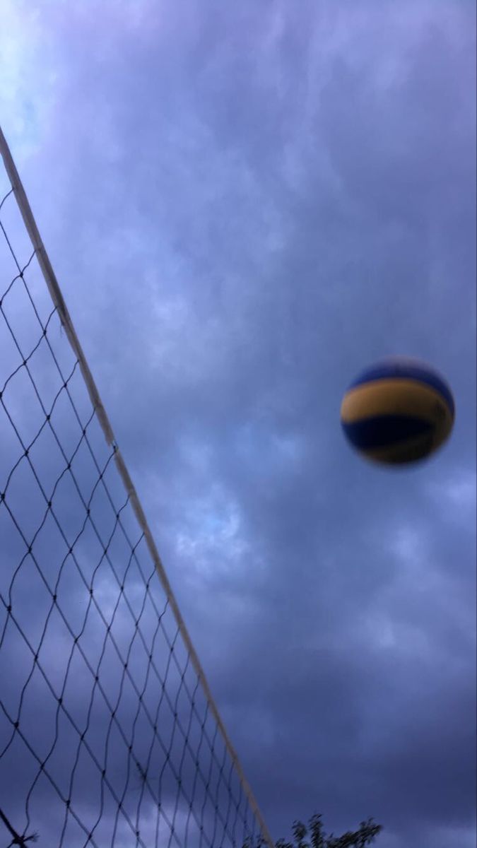 a soccer ball is in the air near a net on a cloudy day with dark clouds