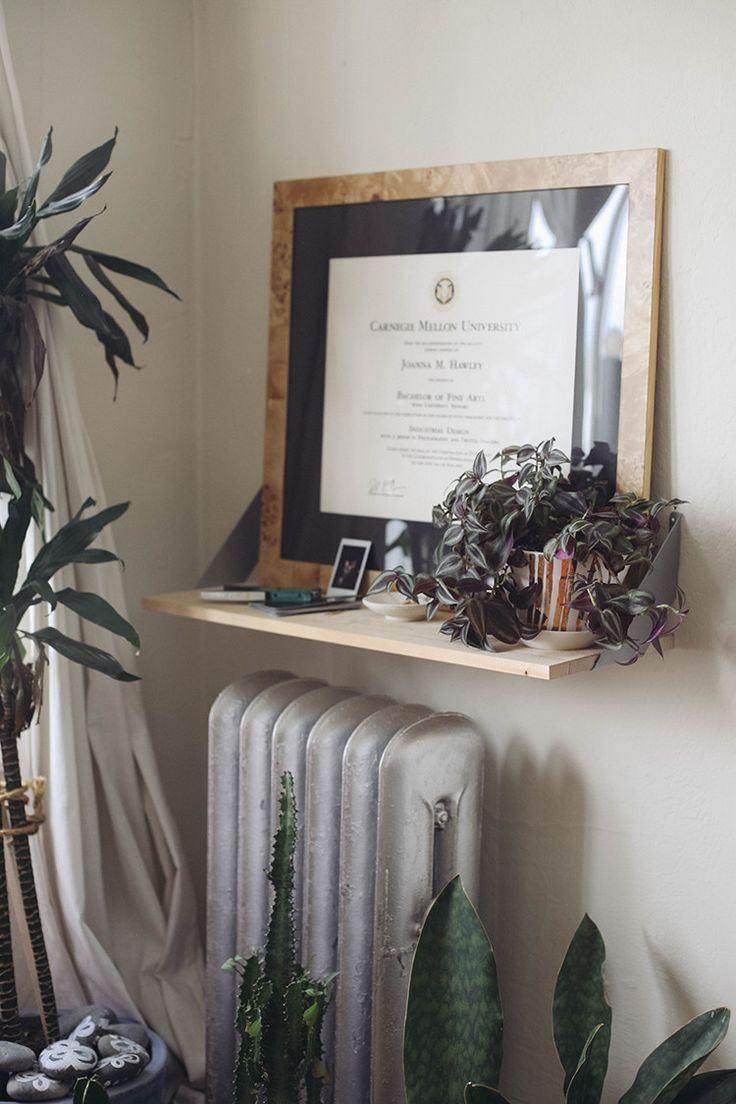 a radiator and some plants on a shelf in front of a framed sign