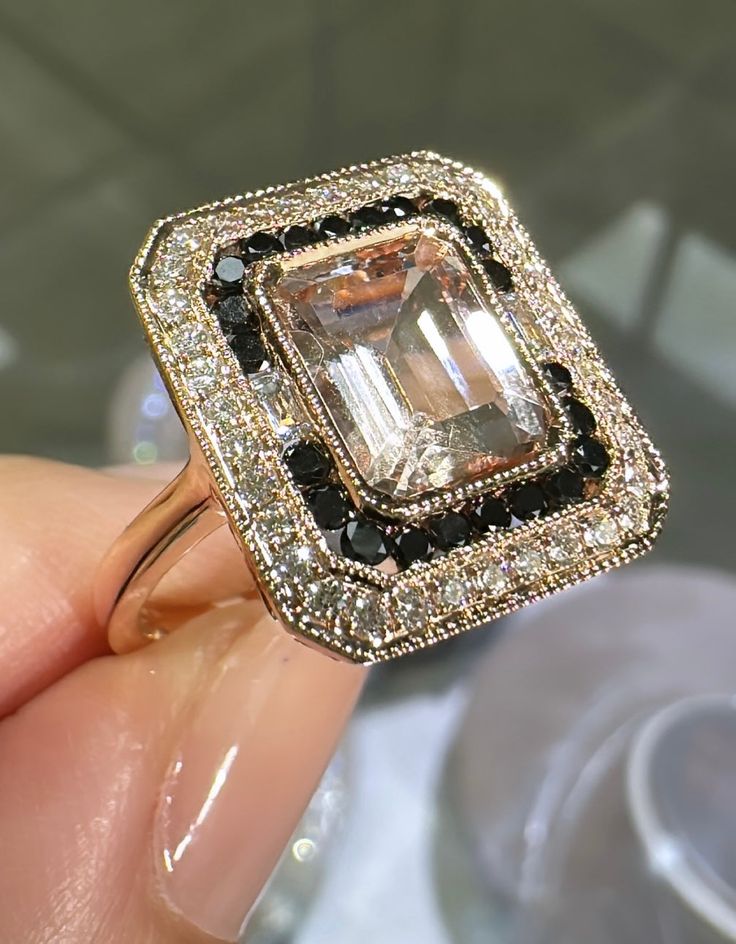 Fall in love with this striking emerald cut morganite and black and white diamond ring. Exquisitely crafted, this gorgeously designed jewelry piece is sure to delight and sparkle. Perfect for any special occasion, this timeless beauty will be treasured forever! Metal: 18K Rose GoldDiamond Shape: Brilliant Round Cut & Baguette CutDiamond Weight: 38 Round cut 0.35ct tw Black Diamonds: 22 Round Brilliant-cuts 0.31ct twGemstone Details: 1 Morganite 2.09carat Estimated production time is 4 - 5 weeks. White Diamond Ring, White Gold Diamond Rings, Black Diamonds, Morganite, Yellow Gold Rings, Emerald Cut, White Diamond, Black Diamond, Round Brilliant