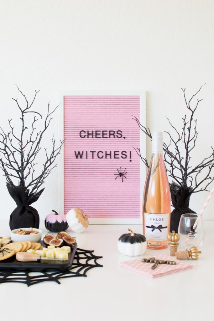 a table topped with wine bottles and halloween decorations next to a sign that says cheers, witches