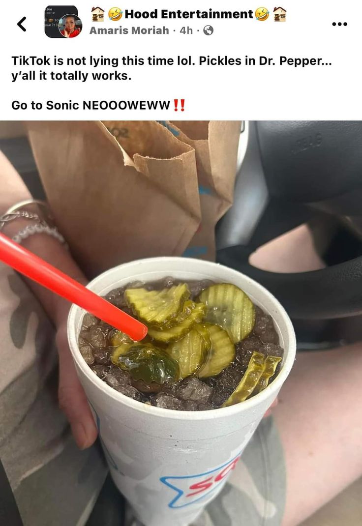 a person holding a cup with pickles in it