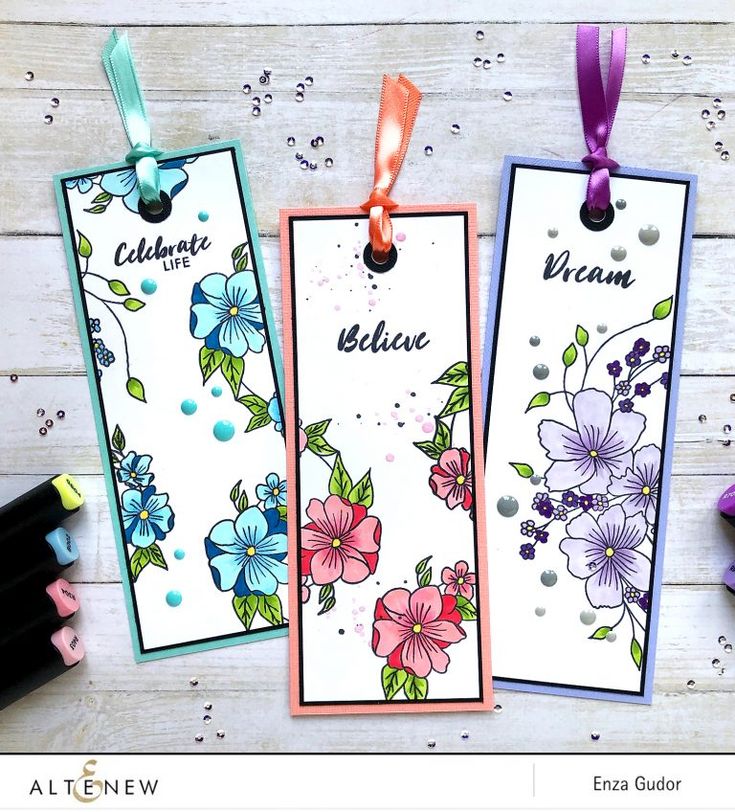 three tags with flowers on them hanging from ribbons