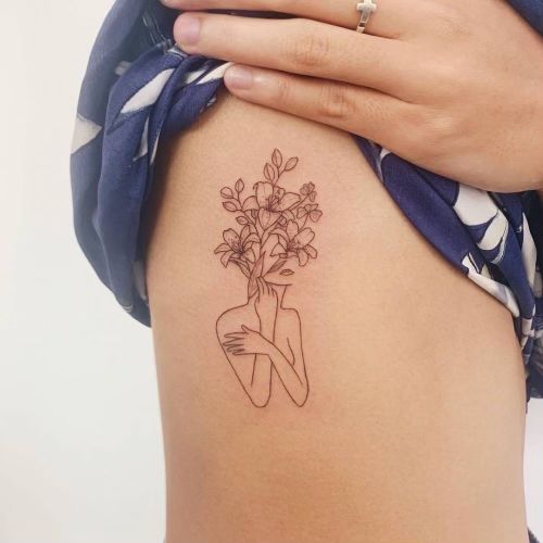 a woman with a tattoo on her stomach holding a bouquet of flowers behind her back