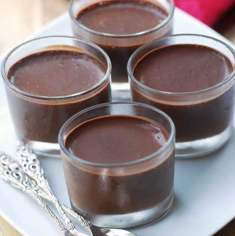 four glasses filled with chocolate pudding on a white plate